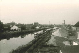 Vers 1960, cliché pris depuis le pont des Vaches. Face à la rue du Chevalier de Barre se trouvent la centrale à béton et ses stocks de matériaux. Les maisons rive gauche sont sous le niveau du fleuve, la pose de palplanches est nécessaire.