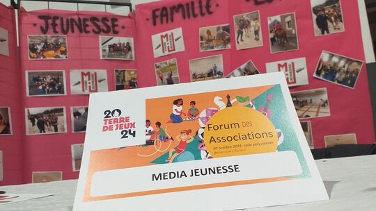 L’image montre un panneau d’exposition divisé en trois sections intitulées « JEUNESSE », « FAMILLE » et « LOISIRS ». Plusieurs photographies et textes sont affichés sur le panneau. Devant celui-ci, un panneau annonce l’événement suivant :
« 20 TERRE DE JEUX 24 – Forum des Associations – 30 octobre 2021 – salle polyvalente – BRUAY-SUR-L’ESCAUT – MEDIA JEUNESSE ».
