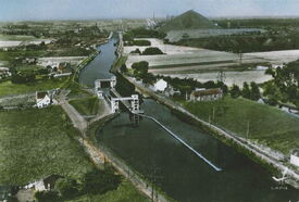 1950, vue aérienne du quartier de la Folie. A gauche, la maison éclusière, et juste devant la petite cabine à partir de laquelle sont commandées les portes de l’écluse. A droite, on devine le Vieil Escaut bordé d’arbres qui va rejoindre le canal une centaine de mètres plus loin.