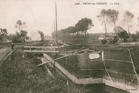 1915, en aval de l’écluse. Ces péniches en bois sont amarrées le long de la rive gauche. En face, rive droite, on peut apercevoir la passerelle du confluent du Vieil Escaut.