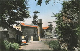 Une vue vers 1950 de la rue du Blanc Pavé qui mène à l’entrée de la fosse. En 1973, les puits sont remblayés et les deux chevalements disparaissent du paysage familier des riverains en 1977.