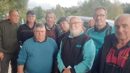 L’image montre un groupe de personnes rassemblées à l’extérieur. Elles sont debout, et leurs visages sont floutés pour préserver leur anonymat. En arrière-plan, on distingue des arbres et un véhicule, suggérant un environnement naturel ou rural. Aucun texte n’est visible dans l’image.
