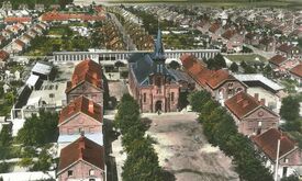 Vue aérienne de la cité vers 1958. Pour éviter l’image négative d’uniformité de la cité, la Compagnie crée autour de la place un lieu de vie et de rassemblement en édifiant église, écoles, dispensaire et salle de fêtes.