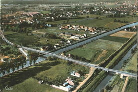 Cliché pris vers 1950. En 1932, une nouvelle route pavée qui démarre juste derrière l’église conduit à Saint-Saulve en franchissant l’Escaut par un pont en fer.